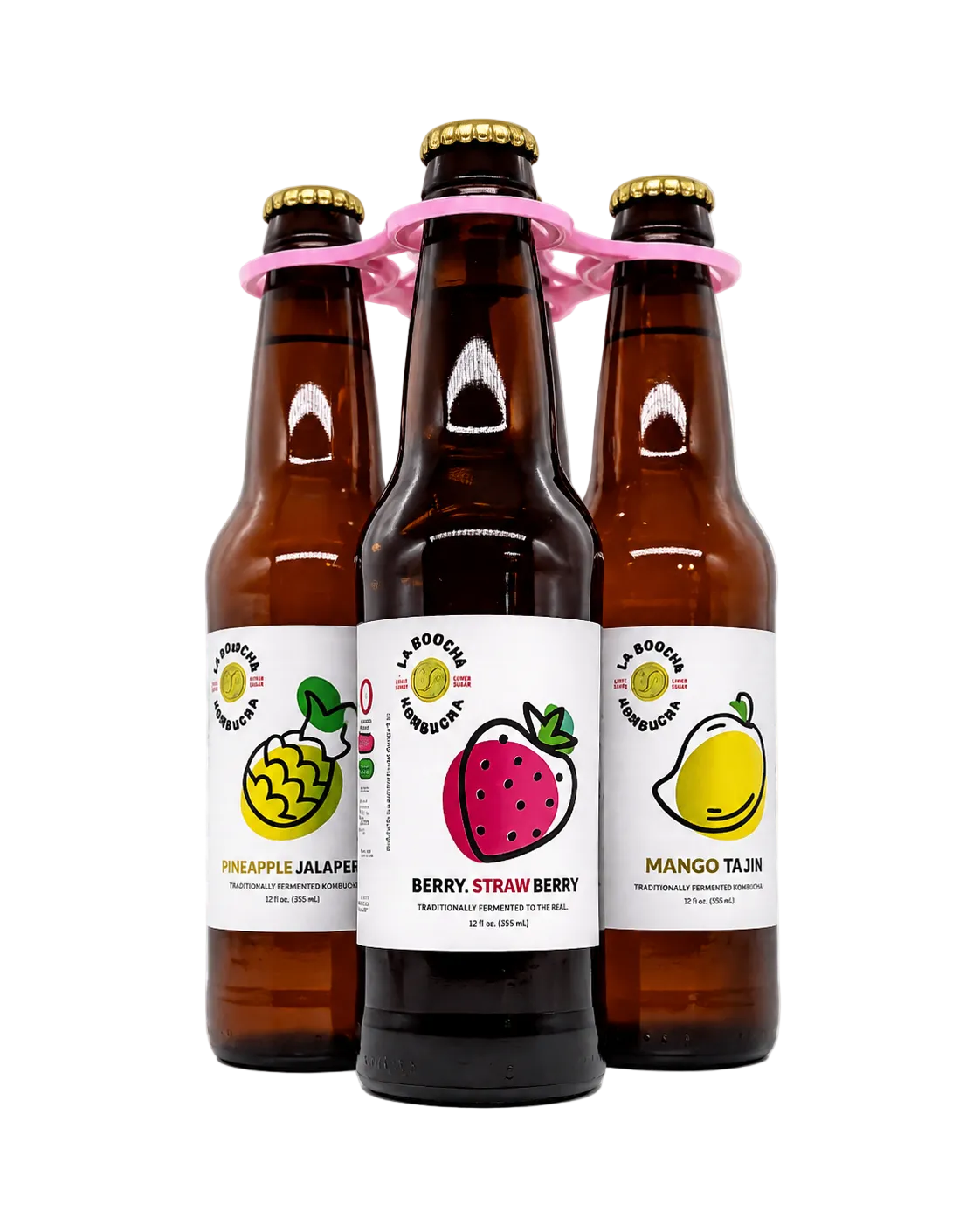 Three brown glass bottles of La Boocha Kombucha fruit kombucha arranged together with a pink plastic carrier loop, on a white and gray checkered background.